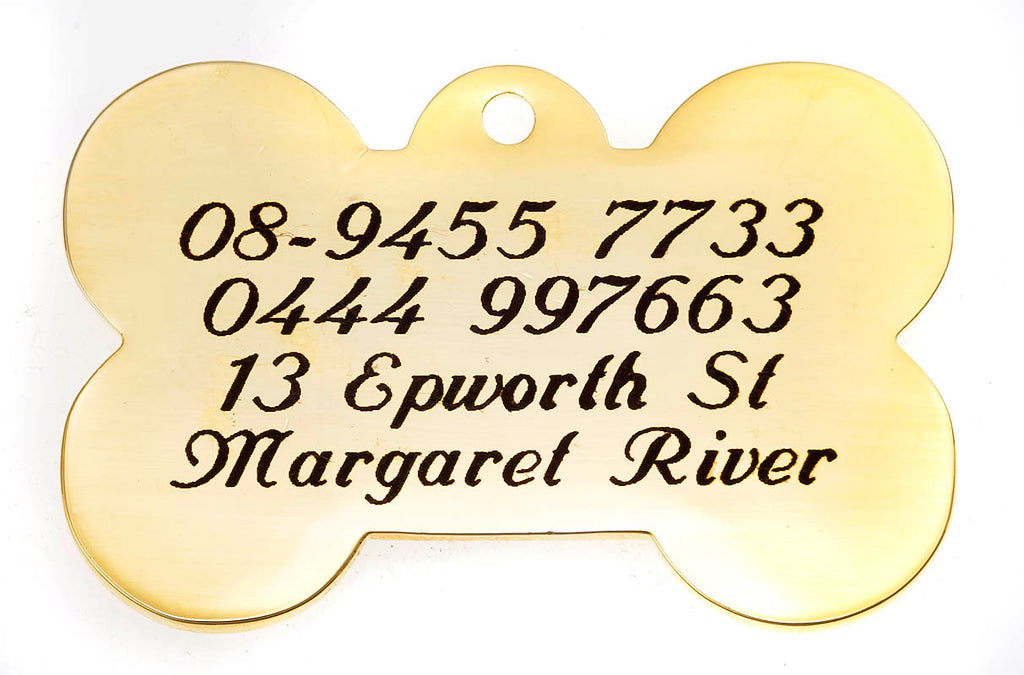 Gold bone-shaped tag with engraved text on a white background